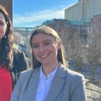 Gothia Forums hälsoekonomer, Emelie Pauli och Stephanie Fledsberg står utomhus. I bakgrunden syns Sahlgrenska Universitetssjukhuset.