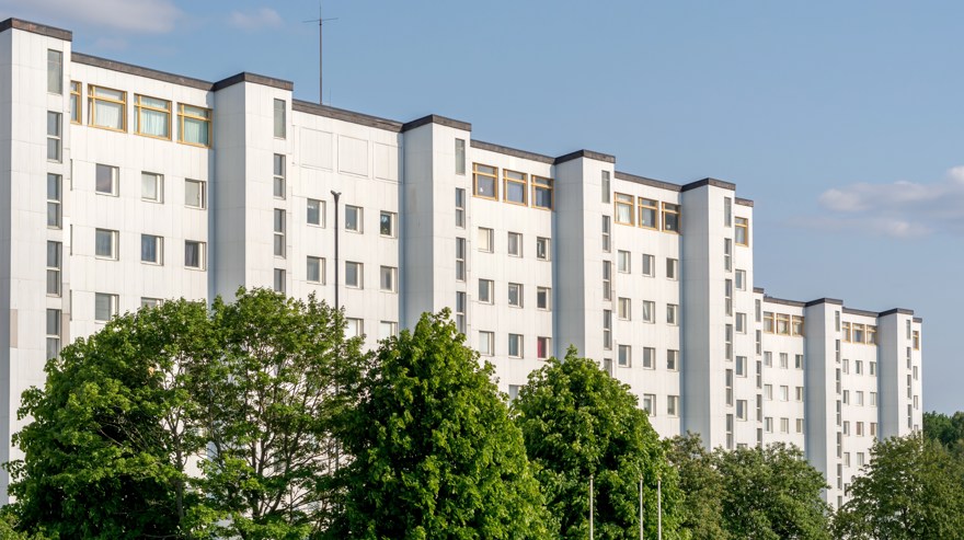 Vit husfasad bakom en allé