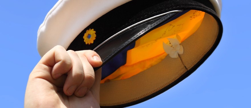 Hand som håller i studentmössa mot blå himmel