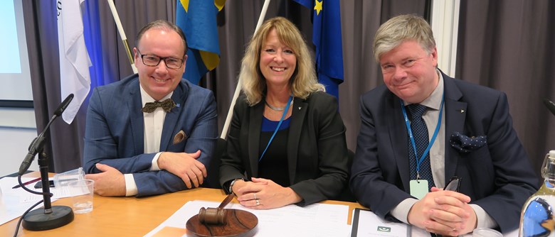 Regionfullmäktiges presidium från 2018 med, från vänster: 2:e vice ordförande Magnus Berntsson (KD), ordförande Annika Tännström (M) och 1:e vice ordförande Per Tenggren (S) sitter vid ett bord.