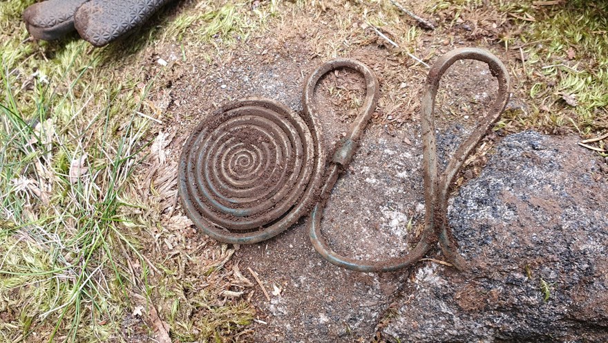 Ett spiralformat bronsåldersföremål ligger på en sten vid fyndplatsen.