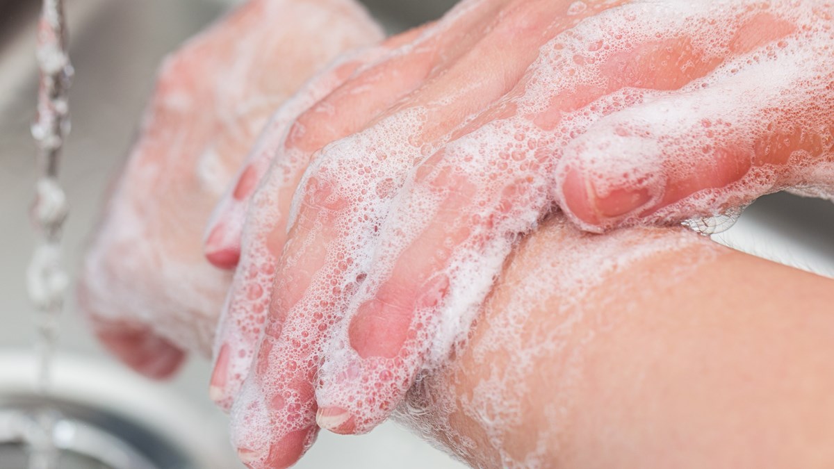 Närbild på när en person tvättar sina händer under rinnande kranvatten.
