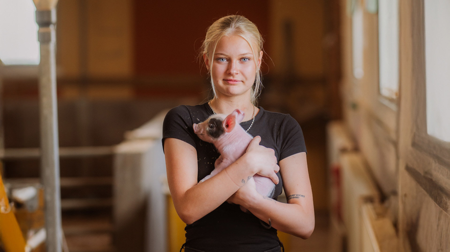 Elev håller griskulting i famnen