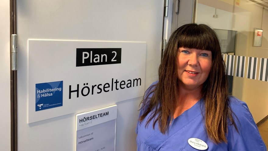 Kvinna står bredvid skylt med texten "plan 2 Hörselteam".