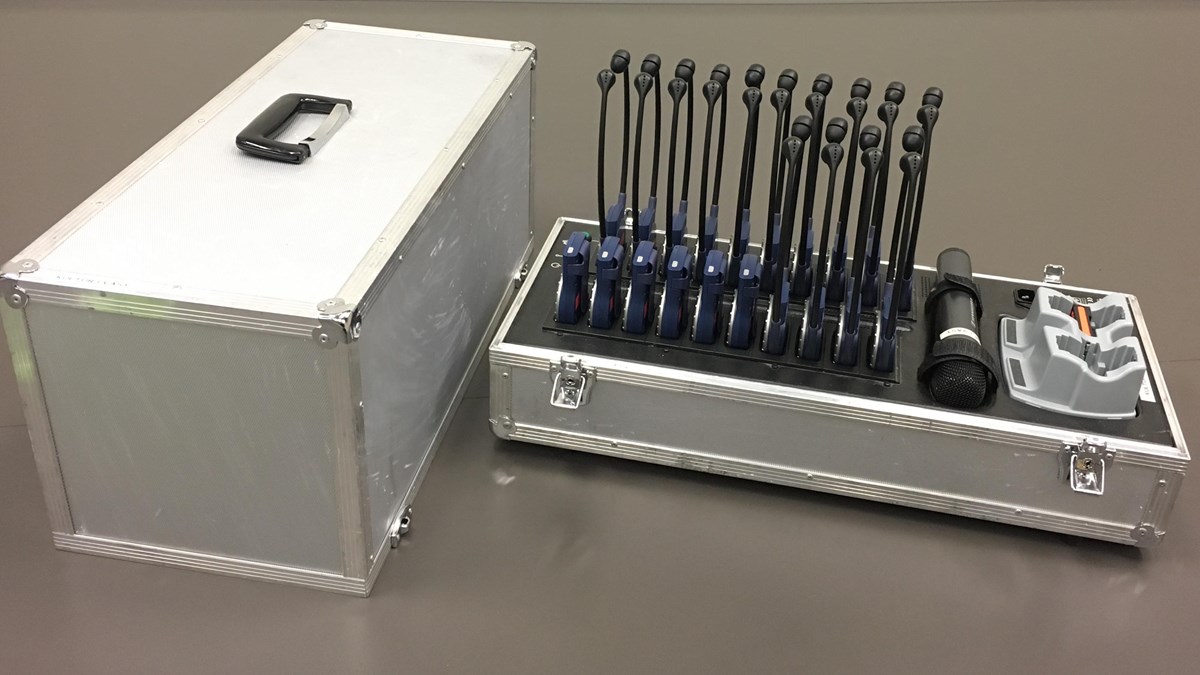 Foto på utrustningen, som består av en metallväska, microfon och flera svarta hörlurar