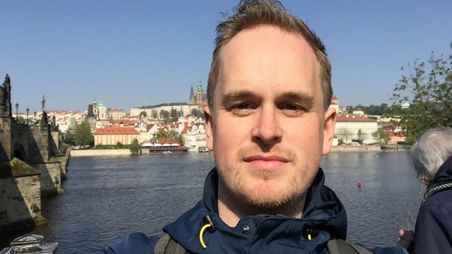 Man i 30-års åldern. Blå kappa, satd bakom honom samt vattendrag.