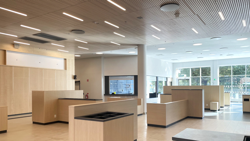 Entréutrymme med plats för väntande. Inredningen är i ljust trä och med stora fönster.