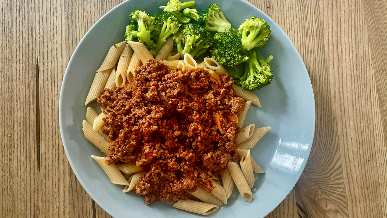 Köttfärssås med pasta och broccoli på en blå tallrik