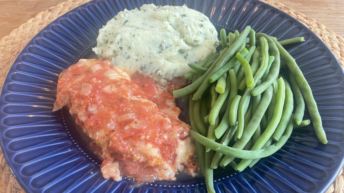 Fiskgratäng med grönt potatismos och haricot verts på en blå tallrik