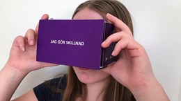 Flicka tittar i VR-glasögon av kartong.
