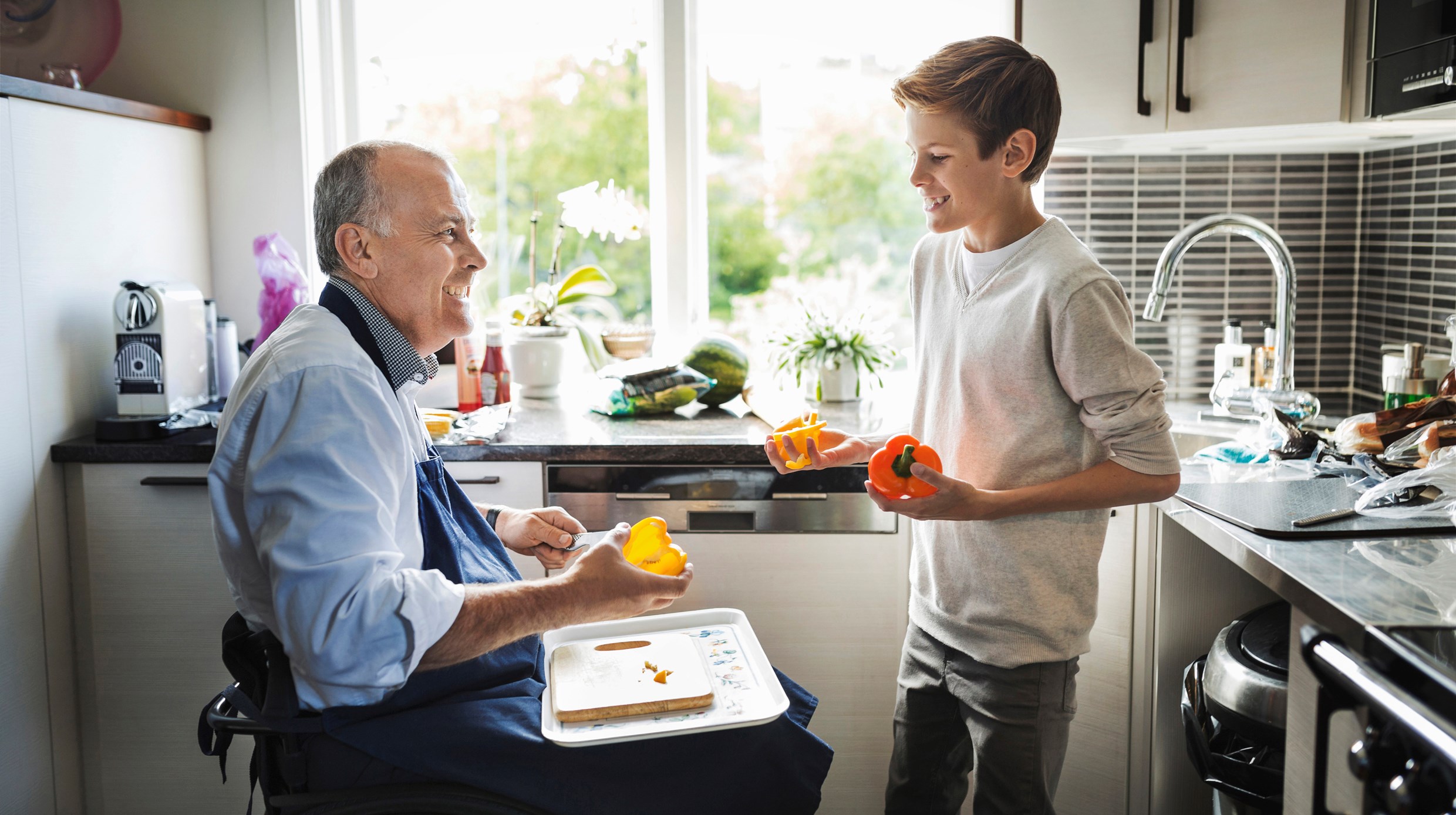 En kille hjälper en man i rullstol i köket