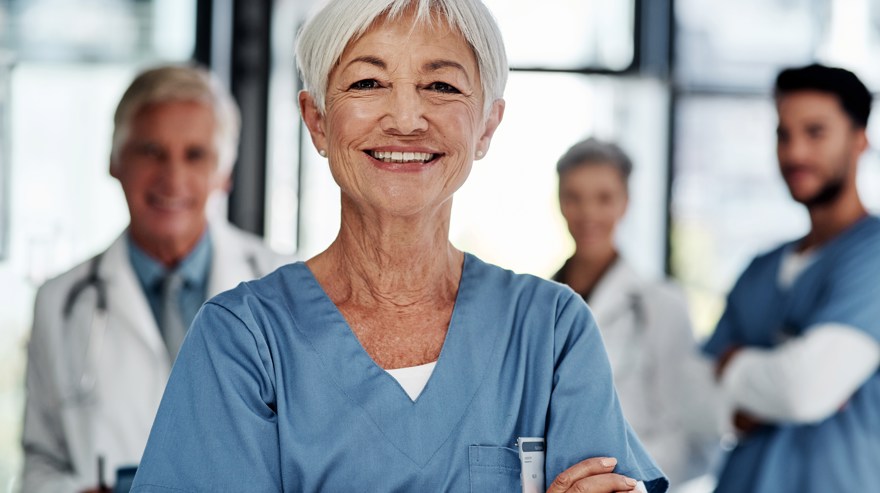 Kvinna i vårdmiljö med kollegor i bakgrunden
