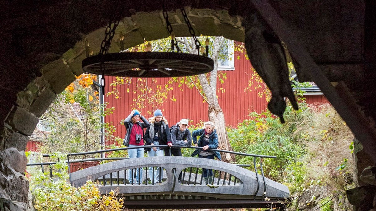 Fyra personer står på en bro utanför ett valv och tittar in.