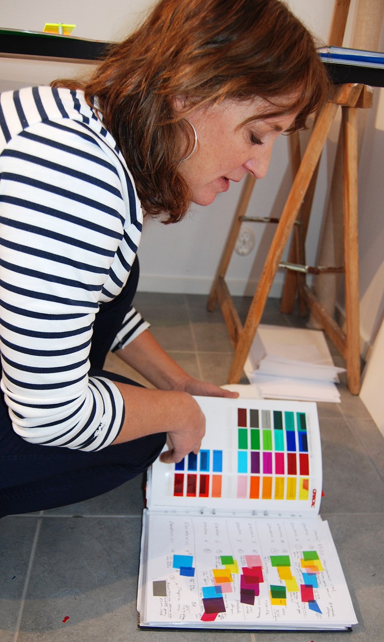 Anna Persson bläddrar bland färgprover hon arbetar med i sitt verk. 