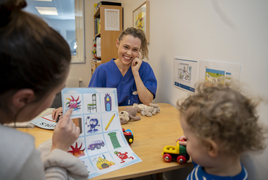 Leende behandlare tittar på ett barn och en förälder