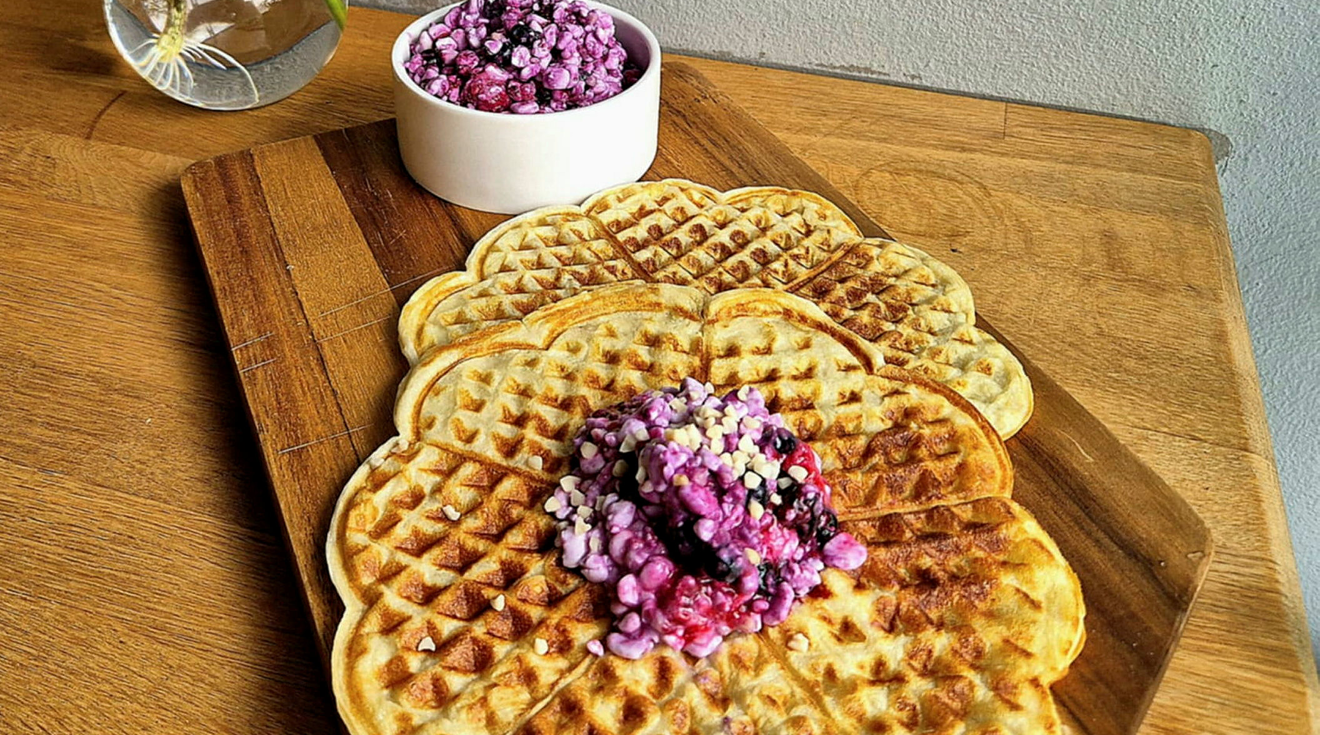 Två våfflor och en skål med keso och bär blandat