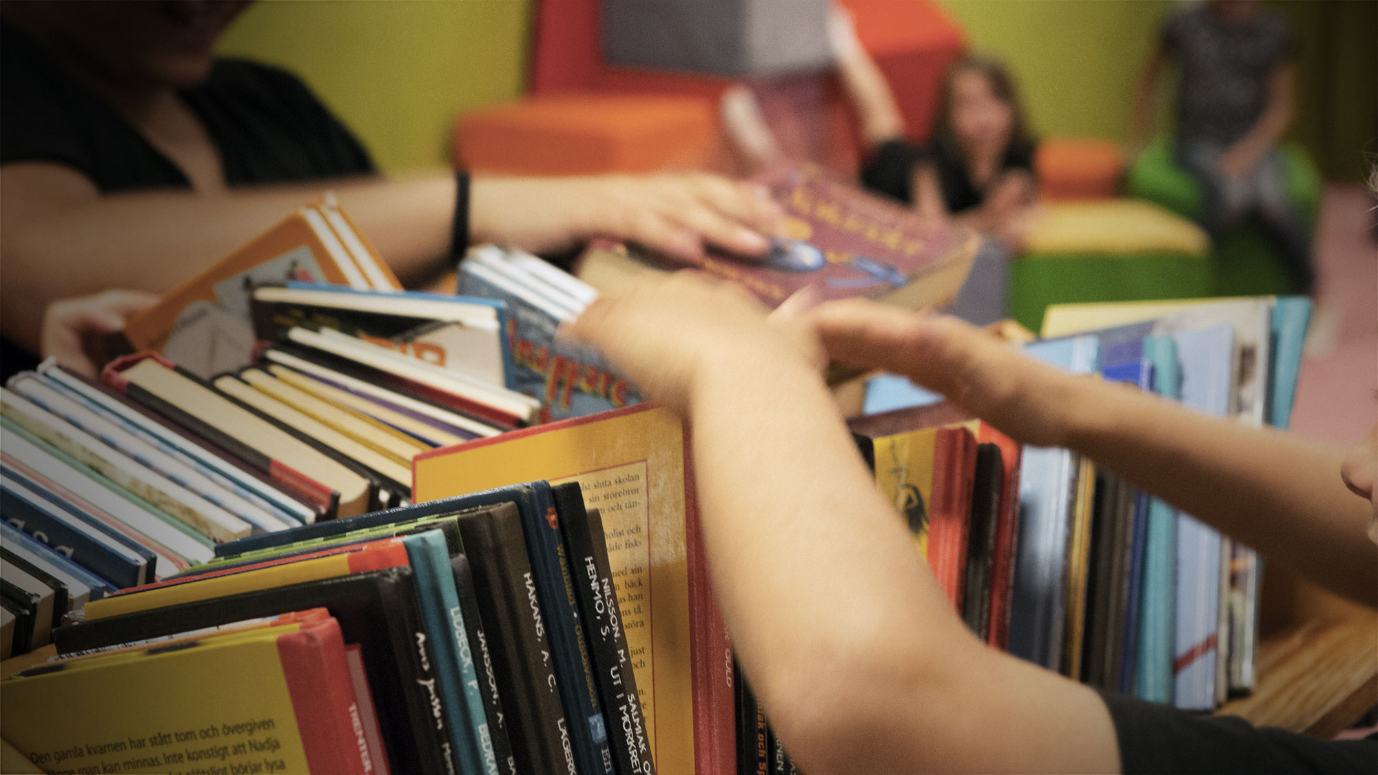 Barn som plockar bland massor av biblioteksböcker.