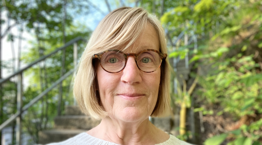 Lillemor Åkerman har blont rakt hår klippt i en page. Hon bär glasögon med bruna bågar och är klädd i en ljus stickad tröja. I bakgrunden finns grönska och en betongtrappa.