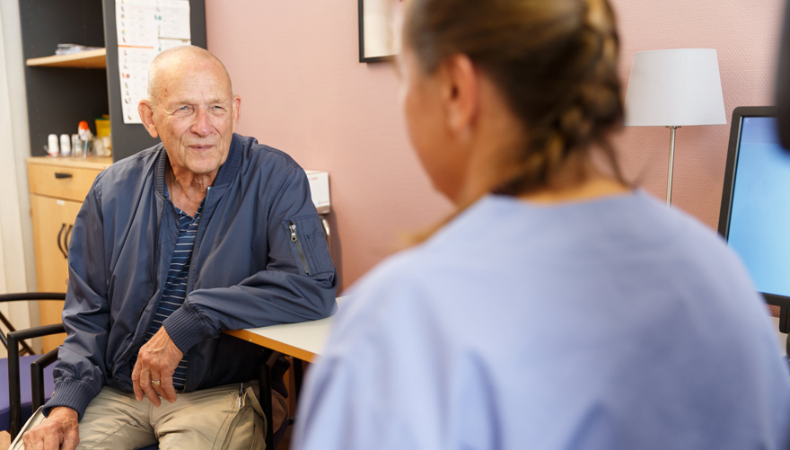 Patientmöte mellan en äldre man och en kvinnlig vårdpersonal