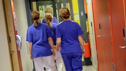 Bild tagen bakifrån på fyra vårdpersonal som går i en korridor