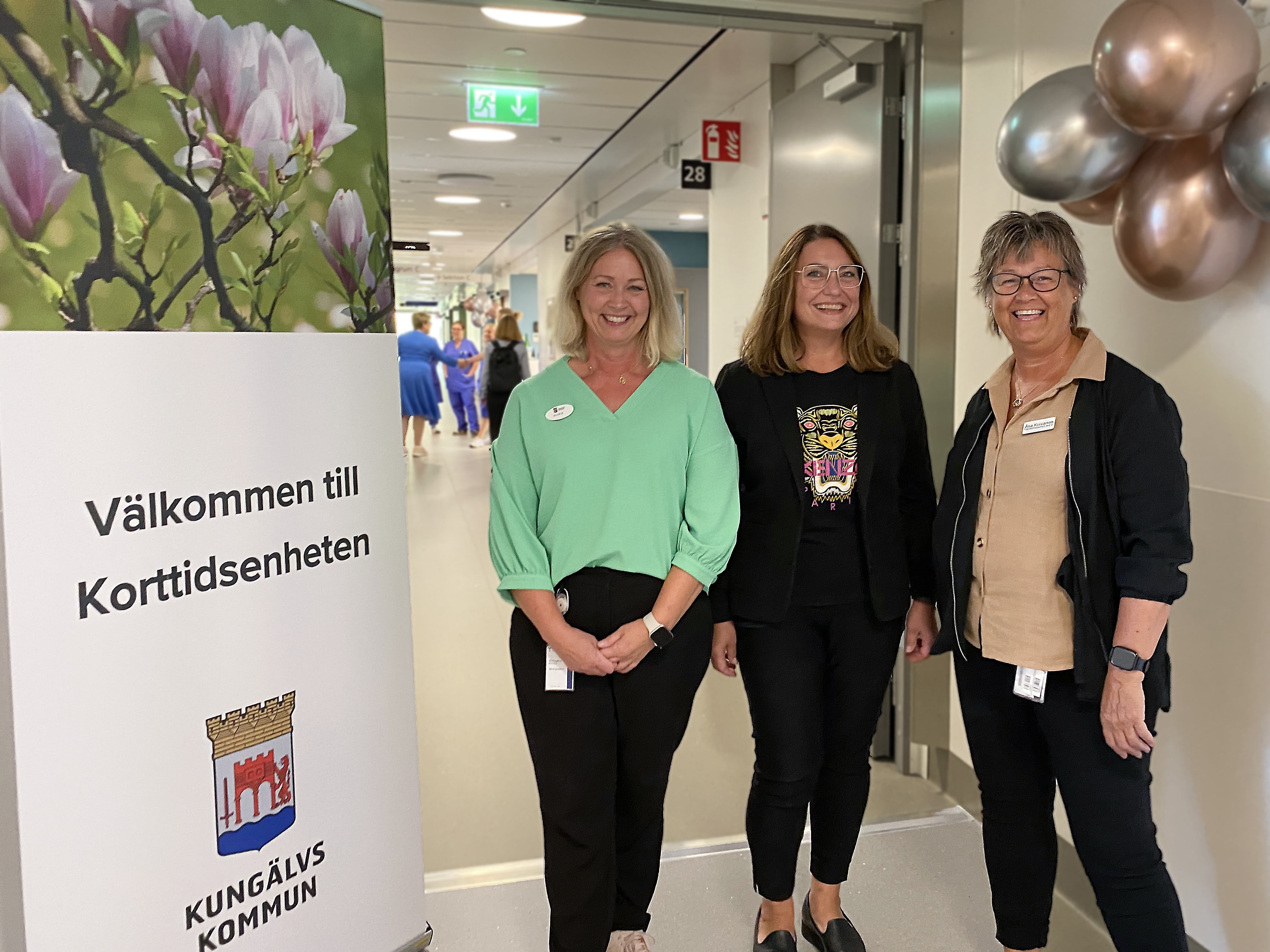 Tre leende kvinnor vid skylt som säger: Välkommen till Korttidsenheten, Kungälvs kommun.