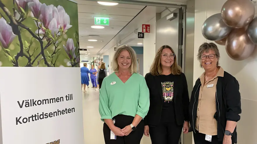 Tre leende kvinnor vid skylt som säger: Välkommen till Korttidsenheten, Kungälvs kommun.