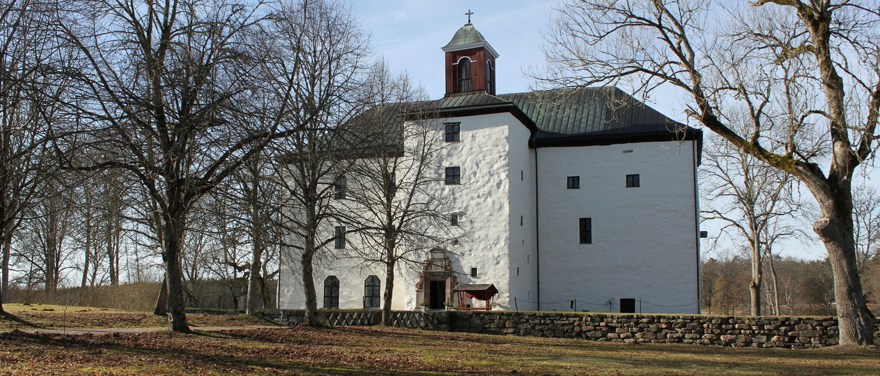 Torpa stenhus i höstsol. Byggnaden är i vit sten med mörkt tak och ett klocktorn.