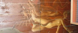En väggmålning på en trävägg föreställande en djävul som biter en människofigur i benet samtidigt som en orm slingrar sig runt benet på människan.