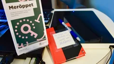 En liten skrivbok i svart och rött ligger på lånedisken. På den står det: För frågor och synpunkter som uppstår vid Meröppet".