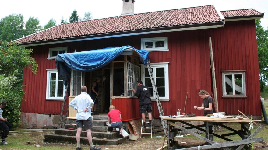 Många människor som renoverar gammalt rött hus.