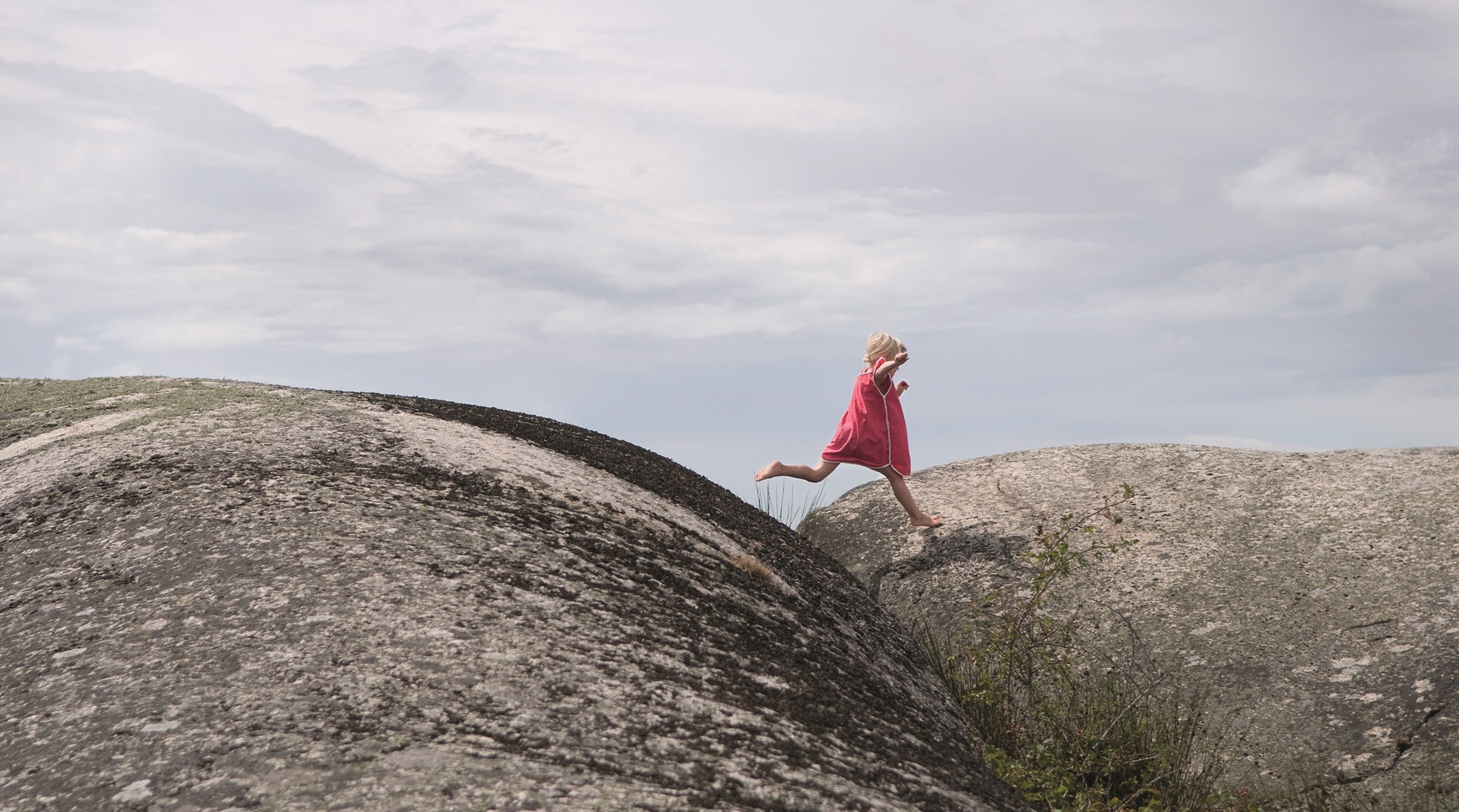 Ett barn som tar ett kliv från en klippa till en annan. Ett metaforiskt steg i ny riktning.