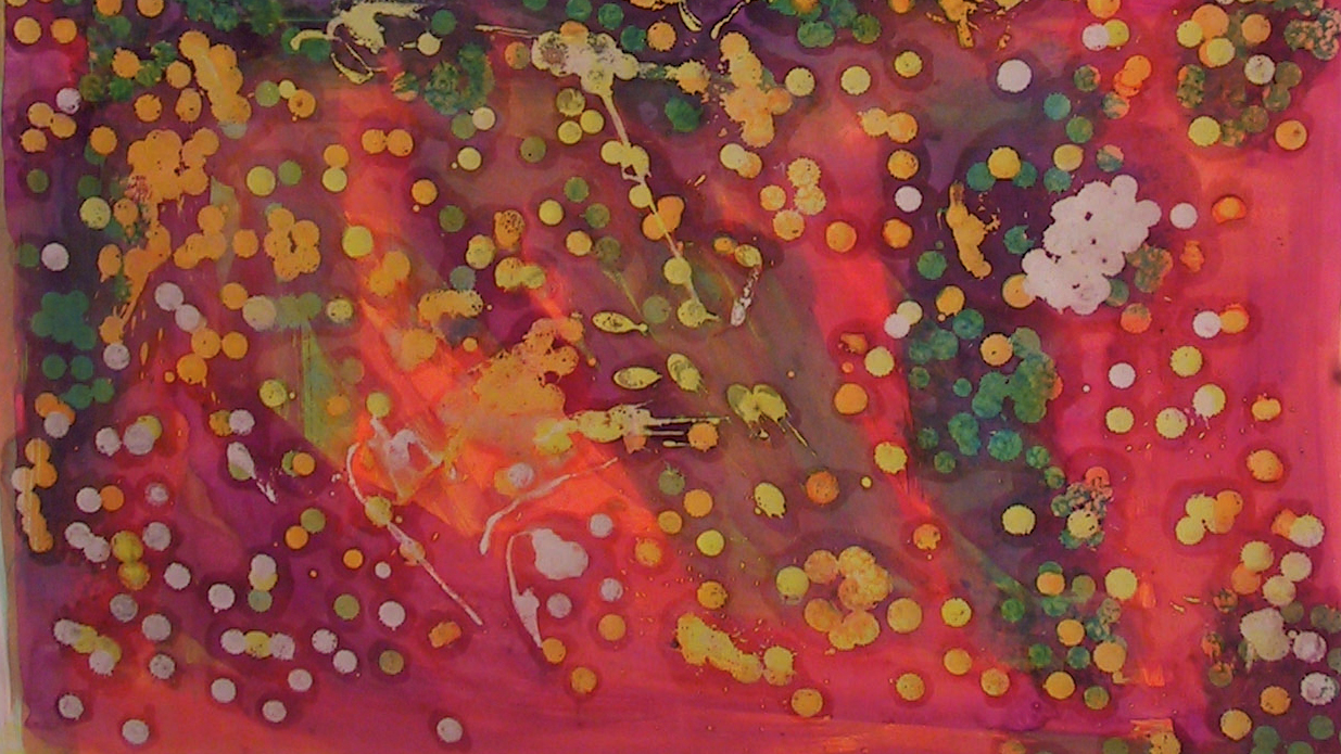 Ett papper med röd-rosa bakgrund med oregelbundna prickar i grönt, gult och vitt.