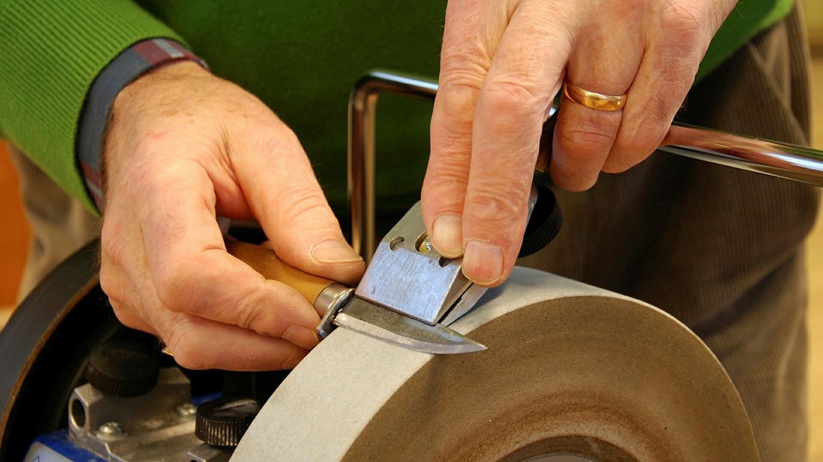 Händer som håller en kniv mot en slipsten