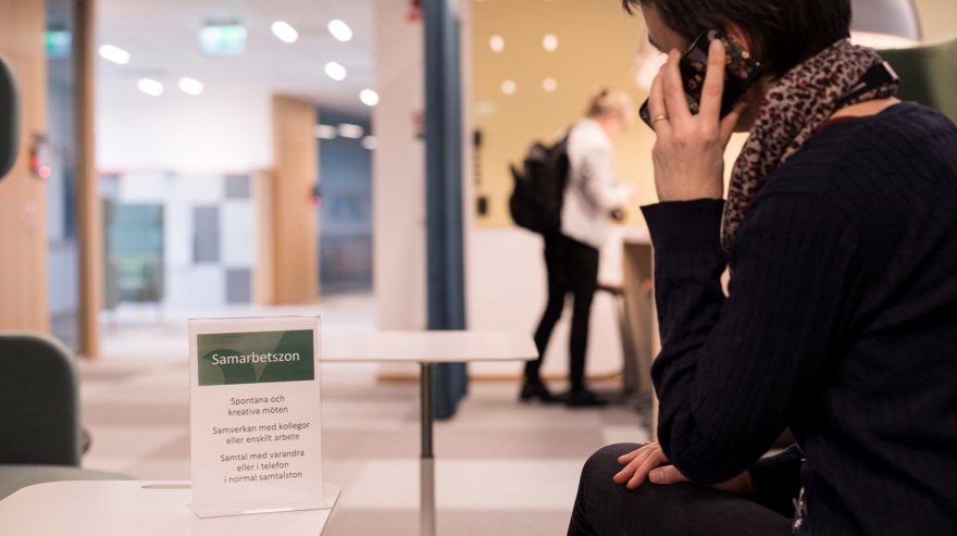 Kvinna talar i mobil i kontorsmiljö