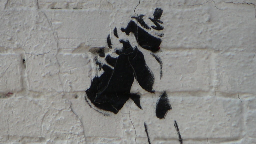 En graffitimålning av en hand som håller i en sprejburk.