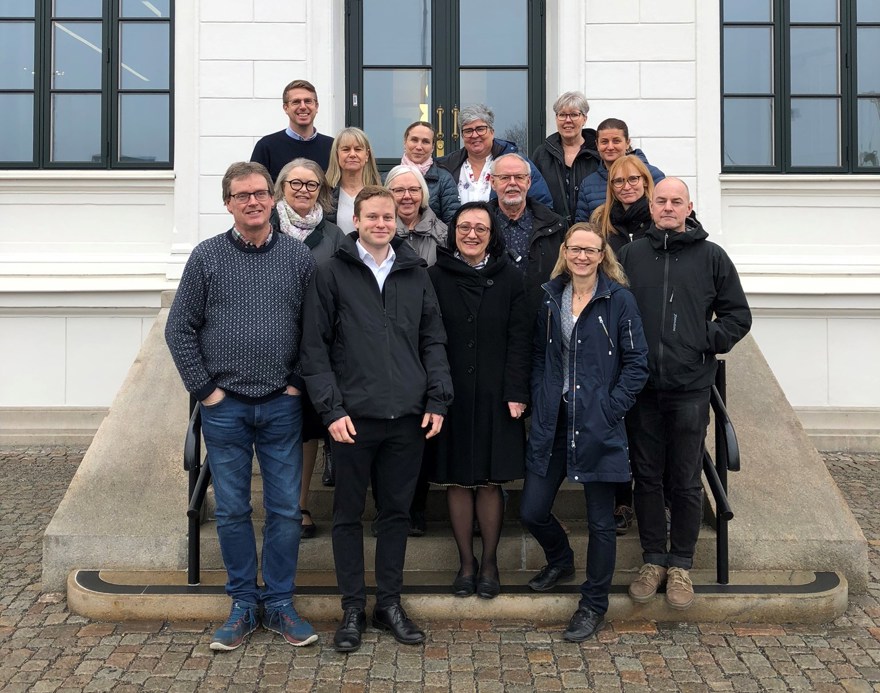 15 kvinnor och män som står tillsammans utomhus i en trappa