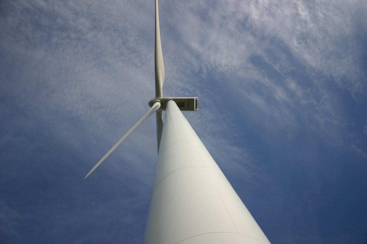 Ett vindkraftverk fotograferat underifrån mot en blå himmel