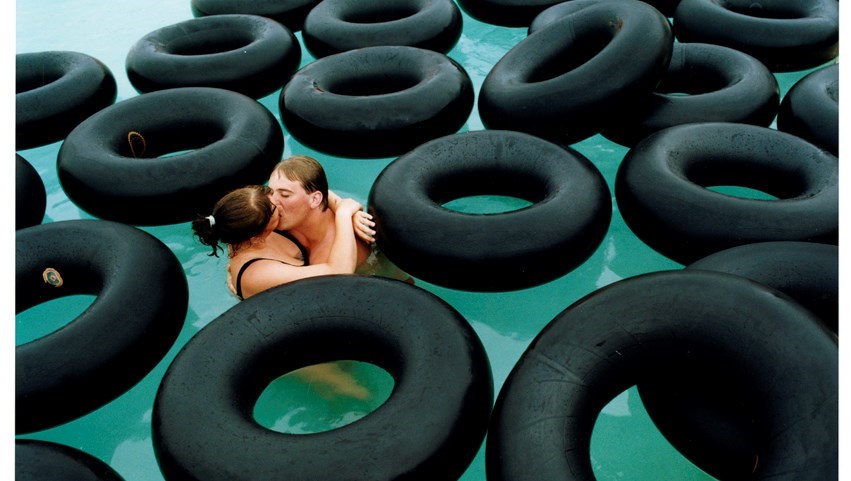Kyssande par i en pool full av svarta badringar