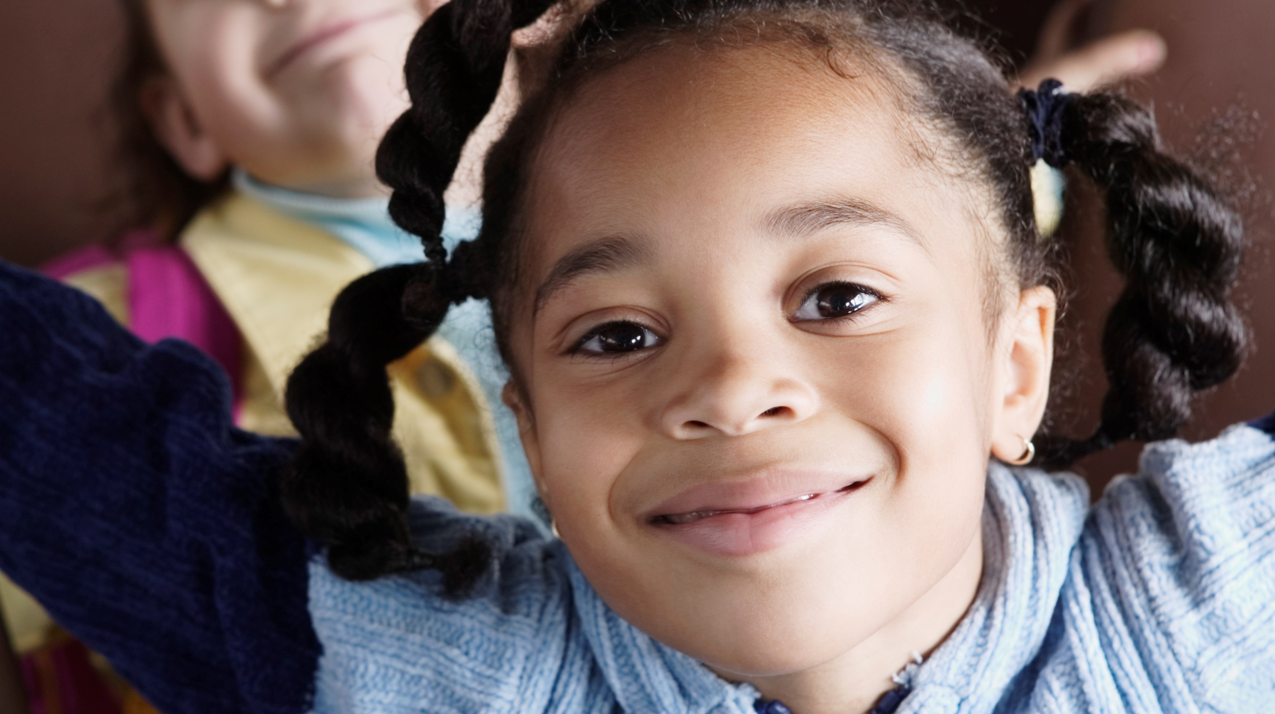 En liten glad flicka tittar fram emot kameran.