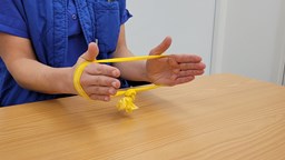 Arbetsterapeut håller i gult gummiband runt händerna