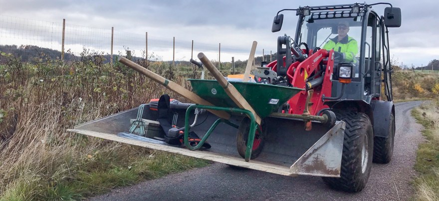 Maskin med skopa lastar verktyg och skottkärra