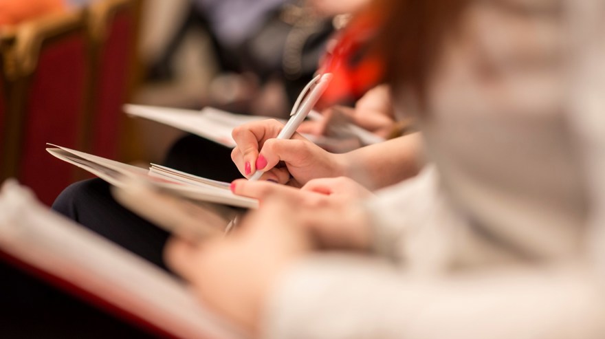 Händer som antecknar på en konferens