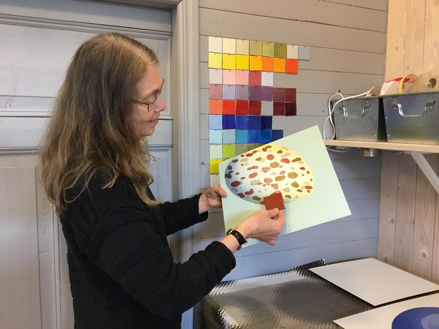 Marie Isaksson jämför färgen från ett emaljerat färgprov med ett av verken.