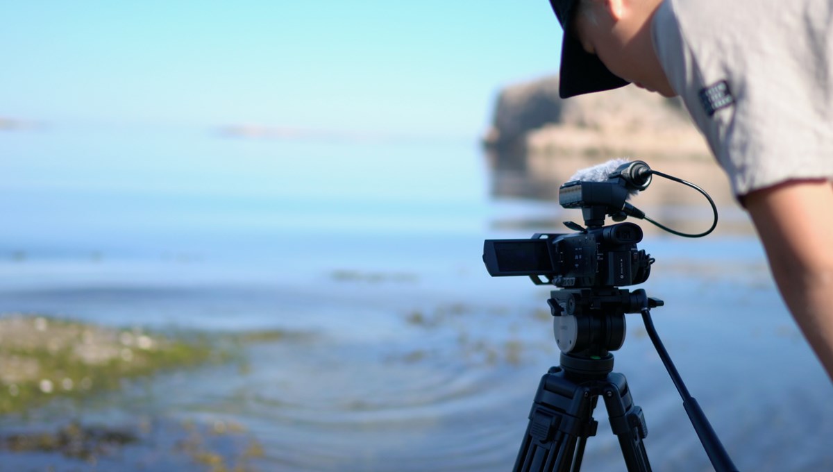 Man med filmkamera filmar havet