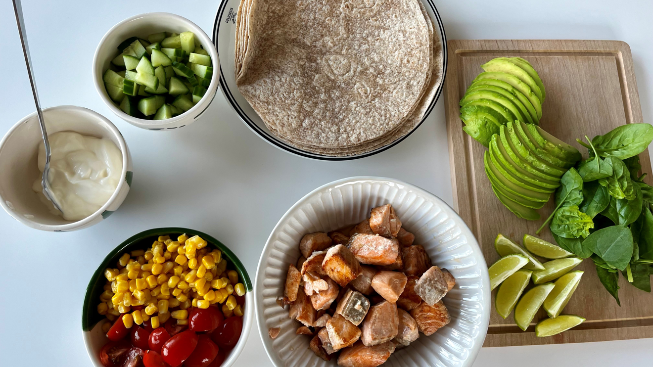 Lax, tortilla och olika grönsaker upplagda i skålar