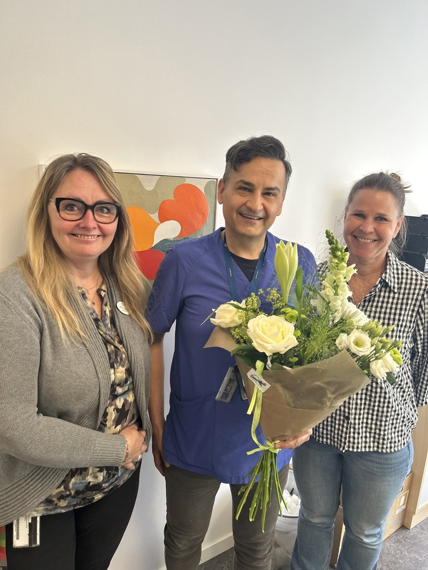 e leende personer och en stor blombukett.