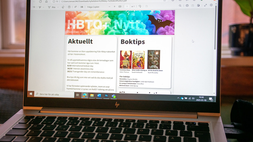 En laptop står uppslagen. På skärmen syns rubrikerna HBTQ+ Nytt, Aktuellt och Boktips.