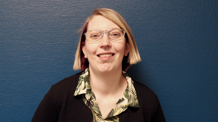 Jessica Fransson har en blond pagefrisyr och bär glasögon med genomskinliga bågar. Bakgrunden är en blåmålad vägg och hon är klädd i en mönstrad skjorta och en svart kofta.