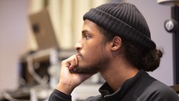 En ung man med svart mössa tittar fokuserat mot någonting utanför bilden.