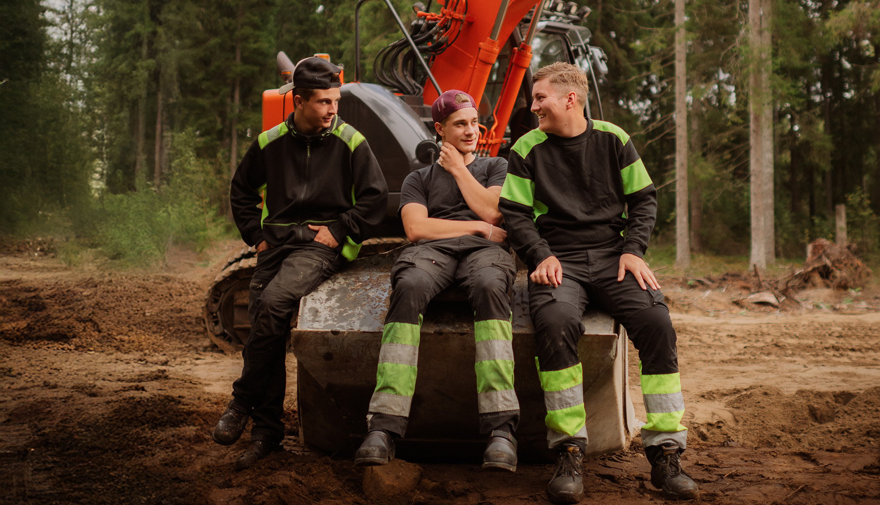 Tre elever sitter på grävskopa